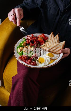 a man has an English breakfast with scrambled eggs, bacon, beans Stock Photo