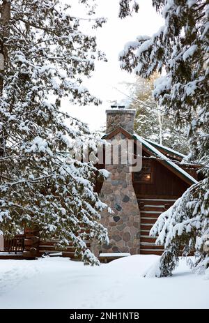 Old log cabin surrounded by snow sitting at the base of a tree covered ...