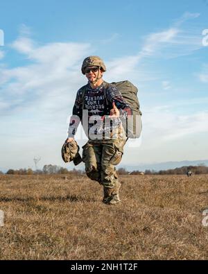 A U.S. Army paratrooper assigned to the 173rd Airborne Brigade shows his excitement as he walks off the drop zone after conducting an airborne operation alongside Italian Army paratroopers with the Brigata Paracadutisti 'Folgore'  at Frida Drop Zone in Pordenone, Italy, while wearing an “ugly holiday sweater” Dec. 7, 2022.     The 173rd Airborne Brigade is the U.S. Army's Contingency Response Force in Europe, providing rapidly deployable forces to the United States European, African, and Central Command areas of responsibility. Forward deployed across Italy and Germany, the brigade routinely t Stock Photo