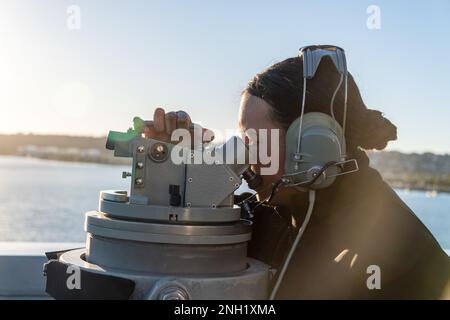 221207-N-VQ947-1130 PACIFIC OCEAN (Dec. 7, 2022) — Quartermaster Seaman Mary Moreno, from Salinas, California, takes a bearing on the bridge wing aboard amphibious transport dock USS Portland (LPD 27) while getting underway from San Diego, Dec. 7, 2022, to support the recovery of NASA’s Orion spacecraft following the launch of Artemis I. Portland, along with Independence-variant littoral combat ship USS Montgomery (LCS 8), is underway in U.S. 3rd Fleet in support of the recovery. The retrieval operation is part of a Department of Defense effort that integrates combatant command and service cap Stock Photo