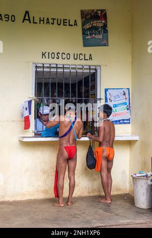Two young indigenous Embera men in traditional dress shopping at a small store by Lake Alajuela in Panama. Stock Photo