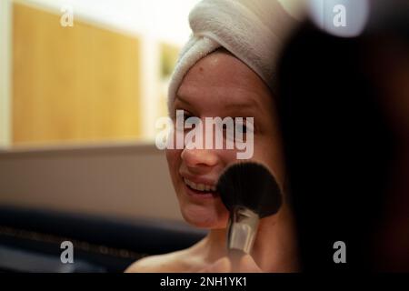selective focus on woman doing makeup sitting in living room after shower, beauty routine. copy space Stock Photo