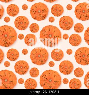 Seamless pattern made of small orange pumpkin on a beige background. Harvesting concept. Stock Photo