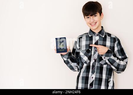 Young teenager boy holding Micronesia passport looking positive and happy standing and smiling with a confident smile against white background. Stock Photo