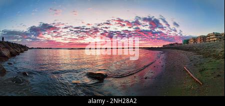 Sun slowly descended towards the horizon, casting a warm golden glow over the tranquil waters of the beach in Rome, Italy. The sky was painted with hu Stock Photo