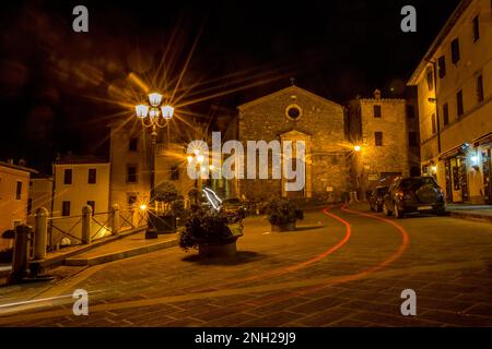 Tuscany, Italy. Night long exposure photograph with car trails, star light effect view of old town. Warm tones and mood. Street travel picture. Stock Photo