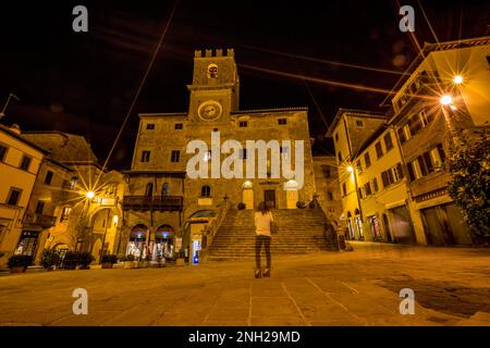 Tuscany, Italy. Night long exposure photograph with ghostly female silhouette, star light effect view of old town. Warm tones and mood. Street travel Stock Photo