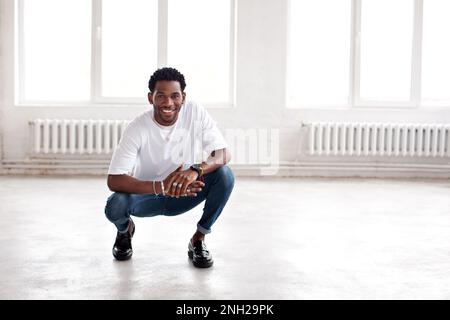Handsome happy man sitting in loft interior inside, smiling. Cool hipster african American guy Stock Photo