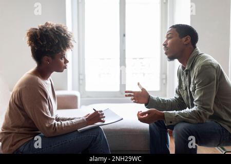 Black man sharing feelings and thoughts with therapist, side view Stock Photo