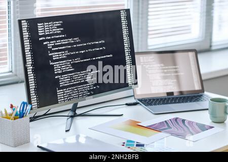 Background image of computer screen with code lines at software designer workplace by window Stock Photo