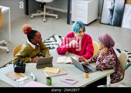 Diverse group of creative young people discussing project during meeting in office focus on Asian man with colored hair Stock Photo