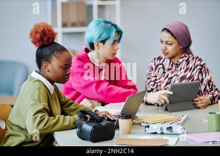 Side view portrait of black young woman using laptop during meeting in office while working with creative tech development team in office, copy space Stock Photo