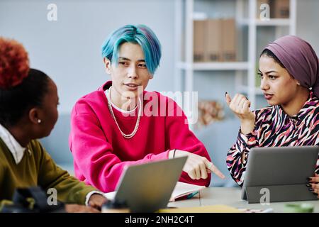 Portrait of young Asian man with colored hair talking to creative team in meeting Stock Photo
