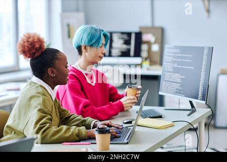 Gen Z creative team working on software programming in office, side view Stock Photo