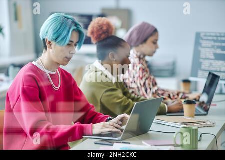 Diverse team of gen Z software developers using computers behind glass while working in office Stock Photo