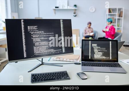 Background image of computer screens with code lines on desk in software development company Stock Photo
