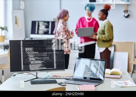 Close up of two computer screen with code lines and blurred creative team in background, copy space Stock Photo