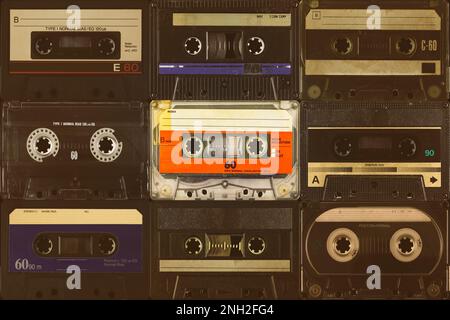 One vintage colorful orange compact cassette in front of black audio tapes Stock Photo