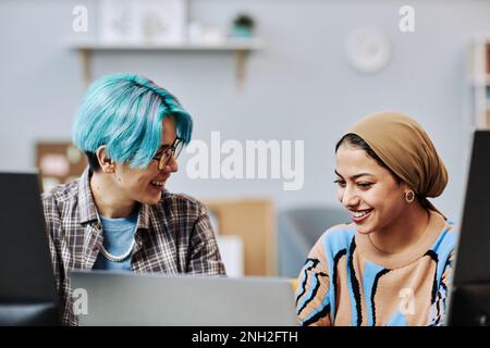 Portrait of two young programmers using computers in office and smiling happily enjoying work Stock Photo