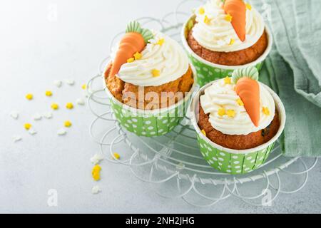 Carrot cake cupcakes for Easter. Carrot cupcakes with cream cheese frosting decorated with tiny marzipan carrots on white background. Happy Easter and Stock Photo