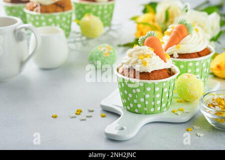 Carrot cake cupcakes for Easter. Carrot cupcakes with cream cheese frosting decorated with tiny marzipan carrots on white background. Happy Easter and Stock Photo