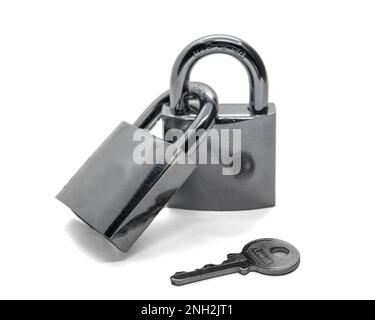 Two steel padlocks linked together and a key, isolated on white background. Stock Photo