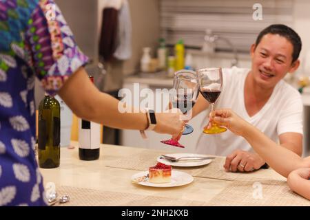 Asian man having a celebration with friends toasting glass of red at dinner party. Stock Photo