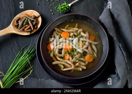 Bavarian, Swabian and Austrian dish -  liver spaetzle in a beef soup served on a dark slate plate Stock Photo