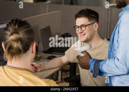 IT Development Team Working on VR Project. Man wearing VR headset, playing and touching something in the virtual world. Diverse men programmers using Stock Photo