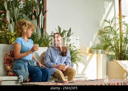 Female friends having drinks and discussing news in cafe Stock Photo