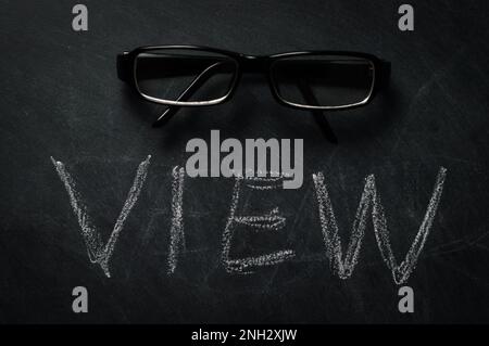 view- word view written in chalk on a blackboard with a pair of glasses on it - concept about the vision and visibility of a person, a product... Stock Photo