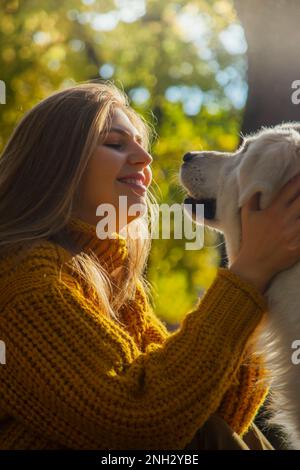 Belgrade, Serbia. November 10th, 2022. Smiling young girl hugging her adorable golden retriever  a park on a sunny day. Stock Photo