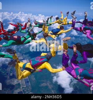 Close-up shot of a group of skydivers, all interlocked while creating a formation while in a free fall Stock Photo