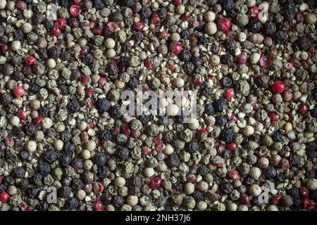 Top-down view of mixed peppercorns in black, white, and green showing diversity in color and texture. Ideal for promoting healthy cooking and adding f Stock Photo