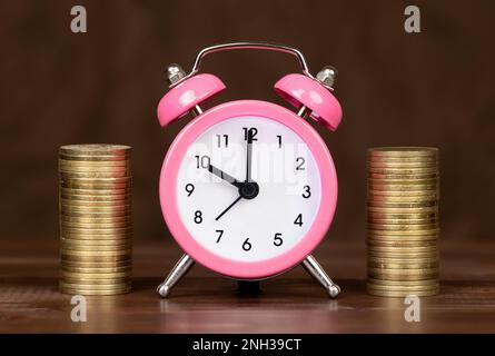 Financial planning. Save money for pension, retirement. Golden coins with alarm clock. Stock Photo