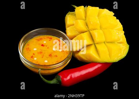 Cutted mango, chili pepper and mango chili sauce isolated on black background. Soft focus Stock Photo