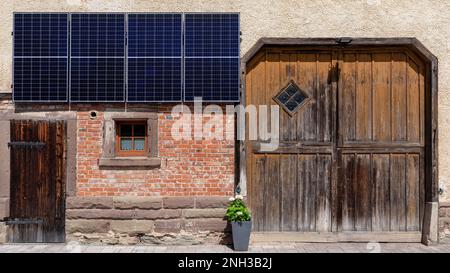 New solar panels on the facade of an old farm building Stock Photo