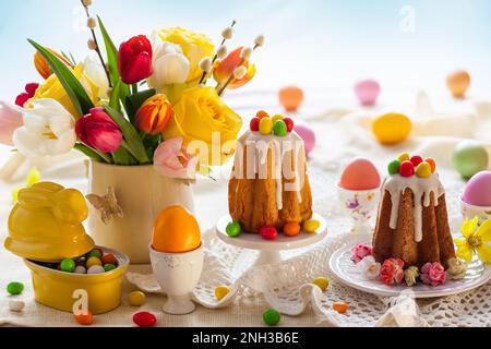 Easter table setting with spring flowers, cakes and easter eggs. Stock Photo