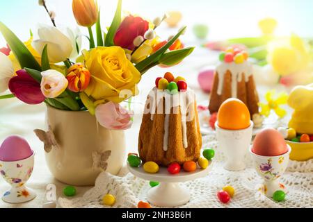 Easter table setting with spring flowers, cakes and easter eggs. Stock Photo