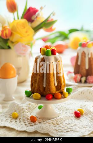 Easter table setting with spring flowers, cakes and easter eggs. Stock Photo