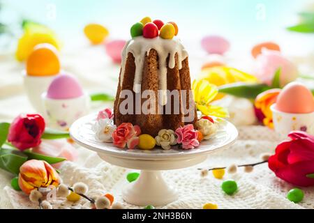 Easter table setting with spring flowers, cakes and easter eggs. Stock Photo