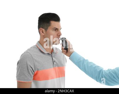 Inspector conducting alcohol breathe testing, man blowing into breathalyzer on white background Stock Photo