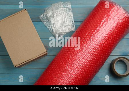 Flat lay composition with bubble wrap roll on light blue background Stock Photo