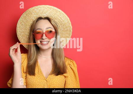 Fashionable young woman chewing bubblegum on red background, space for text Stock Photo