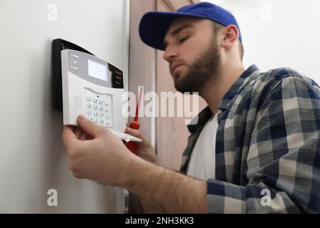 Man installing home security system on white wall in room Stock Photo