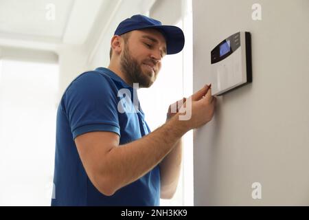 Man installing home security system on white wall in room Stock Photo