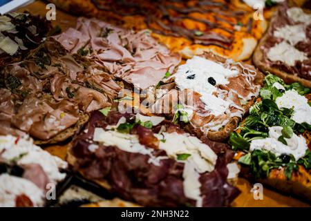 Various flavors pizza cut into square slices on display, in a restaurant. Stock Photo