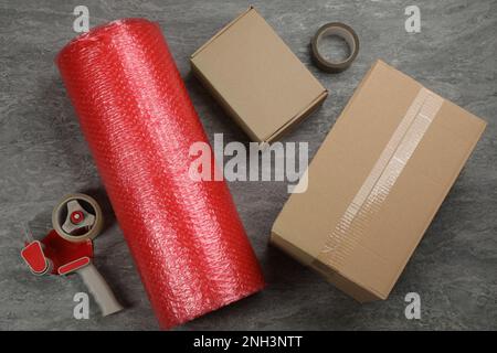 Flat lay composition with bubble wrap roll on grey background Stock Photo