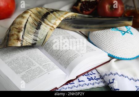 Traditional Rosh Hashanah holiday symbols on table, closeup. Book Torah and tallit with text in Hebrew Stock Photo