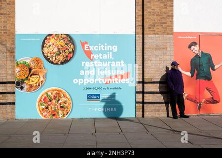 Uxbridge, London Borough of Hillingdon, UK. 9th February, 2023. A man stands next to an advert for retail and restaurant opportunties in the Chimes Shopping Centre. Credit: Maureen McLean/Alamy Stock Photo